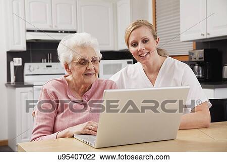 Nurse helping senior woman with laptop View Large Photo Image Stock Image - Nurse helping senior woman with laptop. Fotosearch