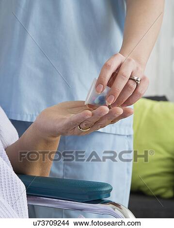 Nurse in nursing home giving pills to senior patient, close-up View Large Photo Image Picture - Nurse in nursing home giving pills to senior patient, close-up. Fotosearch
