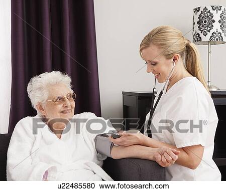 Stock Image - Nurse measuring blood pressure of a senior woman. Fotosearch