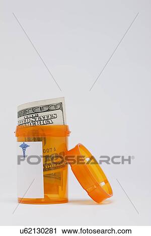 Stock Image - One hundred dollar bill inside pill container, studio shot. Fotosearch