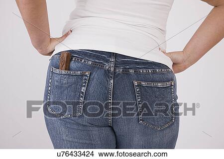 Picture - Overweight woman with chocolate bar in back jeans pocket, mid section, rear view. Fotosearch