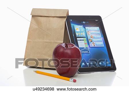 Stock Photo - Paper bag, apple, tablet and pencil on white background. Fotosearch