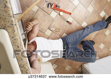 Stock Photo - Plumber fixing kitchen sink. Fotosearch