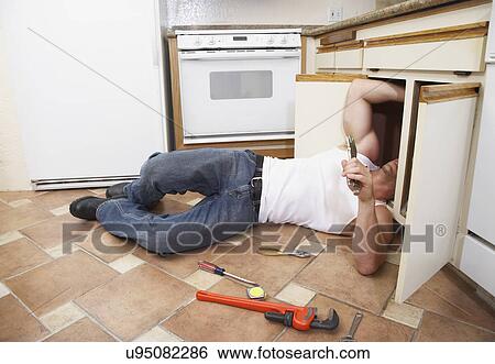Stock Photograph - Plumber fixing kitchen sink. Fotosearch