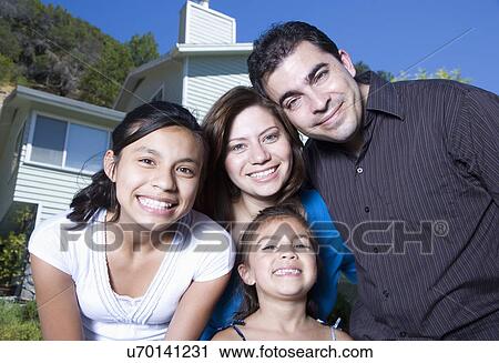 Stock Image - Portrait of family with two girls (8-9, 14-15) in front of house. Fotosearch