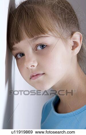 Stock Photo - Portrait of girl (8-9) leaning against wall. Fotosearch