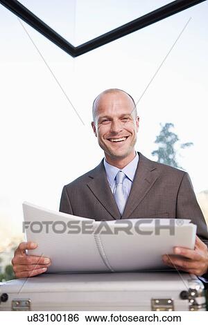 Portrait of mid adult businessman holding file, smiling View Large Photo Image Stock Photograph - Portrait of mid adult businessman holding file, smiling. Fotosearch