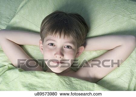 Portrait of smiling boy (8-9) lying in bed View Large Photo Image Stock Image - Portrait of smiling boy (8-9) lying in bed. Fotosearch