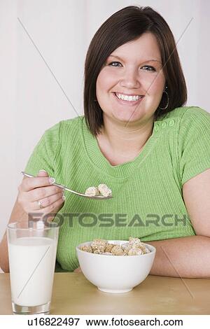 Portrait of smiling young woman eating healthy breakfast View Large Photo Image Stock Photo - Portrait of smiling young woman eating healthy breakfast. Fotosearch