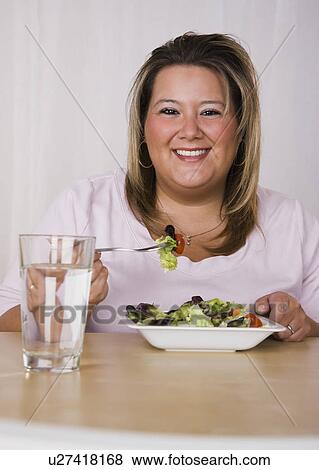 Stock Photo - Portrait of smiling young woman eating salad. Fotosearch