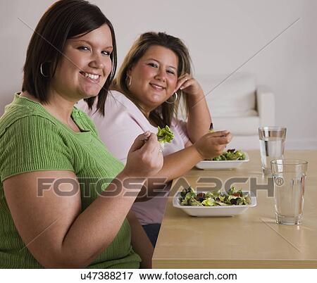 Stock Photo - Portrait of two smiling women eating salads. Fotosearch