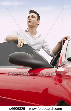 Portrait of young man standing next to red car View Large Photo Image Stock Image - Portrait of young man standing next to red car. Fotosearch