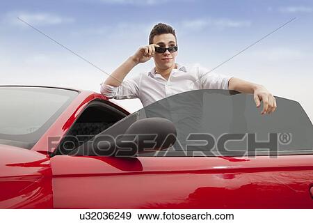 Portrait of young man standing next to red car View Large Photo Image Stock Photo - Portrait of young man standing next to red car. Fotosearch