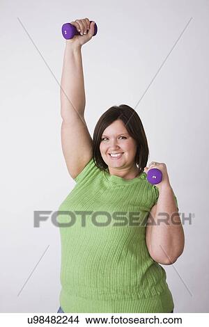 Picture - Portrait of young overweight woman exercising with dumbbells . Fotosearch