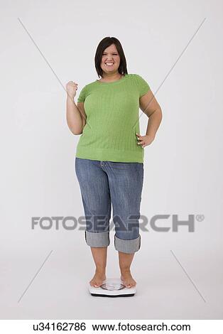 Portrait of young overweight woman standing on scales and cheering View Large Photo Image Stock Photograph - Portrait of young overweight woman standing on scales and cheering. Fotosearch