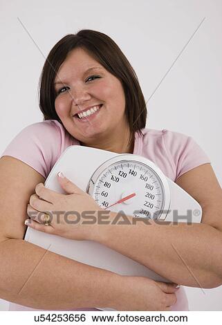 Portrait of young overweight woman hugging scales and smiling View Large Photo Image Stock Photograph - Portrait of young overweight woman hugging scales and smiling. Fotosearch