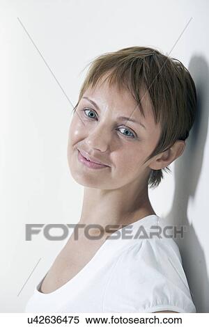 Portrait of young smiling woman leaning against wall View Large Photo Image Stock Photography - Portrait of young smiling woman leaning against wall. Fotosearch
