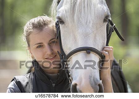 Picture - Portrait of young woman embracing horse. Fotosearch