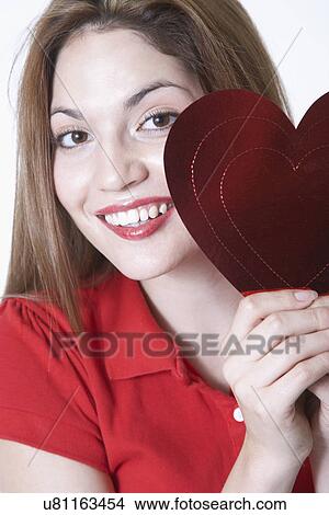 Picture - Portrait of young woman holding heart shape Valentine card. Fotosearch
