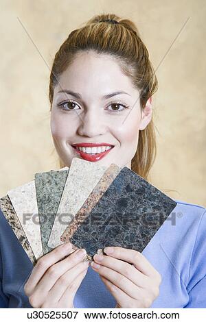 Stock Photo - Portrait of young woman holding countertop samples. Fotosearch