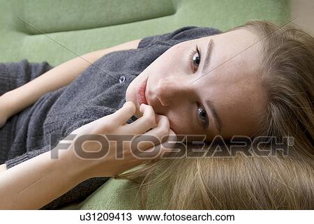 Stock Image - Portrait of young woman relaxing on sofa. Fotosearch