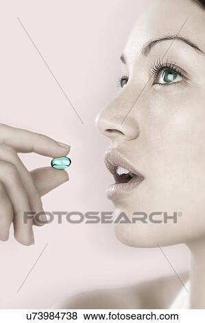 Stock Photo - Profile of young woman taking blue pill. Fotosearch