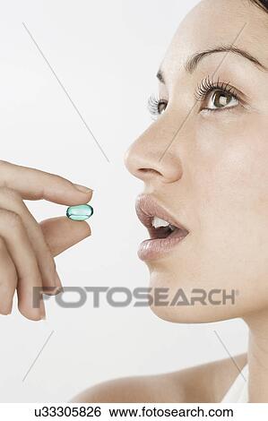 Profile of young woman taking blue pill View Large Photo Image Stock Photograph - Profile of young woman taking blue pill. Fotosearch