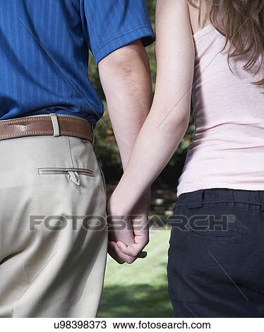 Rear view of young couple holding hands, mid section View Large Photo Image Stock Image - Rear view of young couple holding hands, mid section. Fotosearch