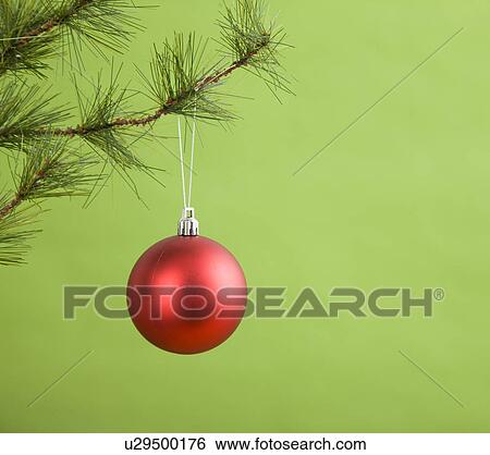 Stock Photograph - Red bauble hanging from Christmas tree. Fotosearch