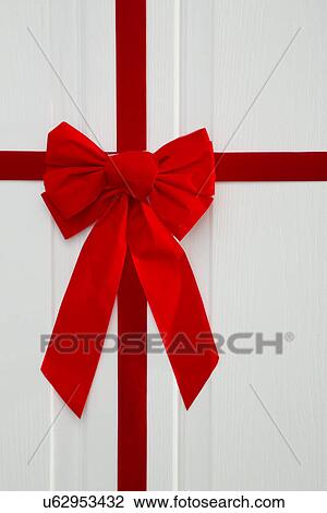 Stock Image - Red bow on white door. Fotosearch