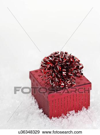 Stock Photo - Red Christmas gift on snow. Fotosearch