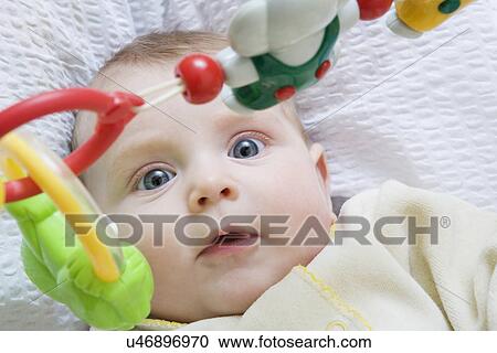 Stock Image - Russia, Voronezh, Baby (0-1month) lying in bed, looking at hanging toys. Fotosearch