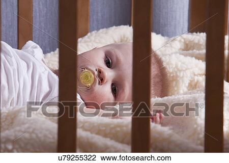 Stock Image - Russia, Voronezh, baby boy (12-17 months) in crib. Fotosearch