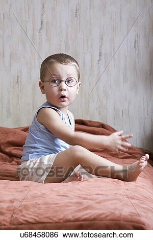 Stock Photograph - Russia, Voronezh, Boy (2-3) sitting on bed. Fotosearch