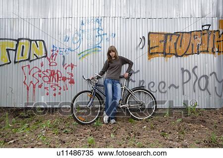 Stock Photography - Russia, Voronezh, girl (14-15) with bike leaning against wall with graffiti. Fotosearch