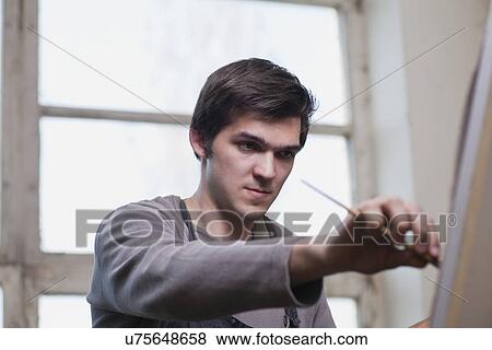 Stock Photo - Russia, Voronezh, man painting on canvas. Fotosearch