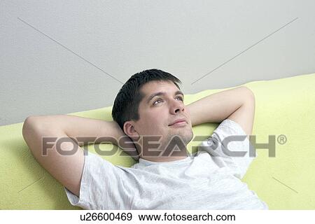 Russia, Voronezh, Pensive young man reclining on sofa View Large Photo Image Stock Photo - Russia, Voronezh, Pensive young man reclining on sofa. Fotosearch
