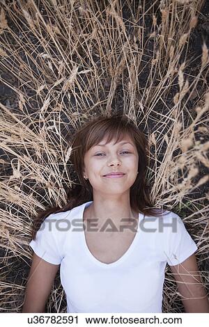 Stock Image - Russia, Voronezh, portrait of young woman lying in wheat. Fotosearch