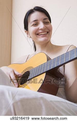 Stock Photo - Russia, Voronezh, Smiling woman playing guitar. Fotosearch