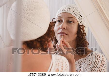 Stock Photo - Russia, Voronezh, woman applying cosmetics in front of mirror. Fotosearch