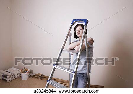 Picture - Russia, Voronezh, woman leaning on ladder in room. Fotosearch