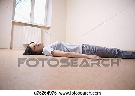 Stock Photograph - Russia, Voronezh, woman lying on floor in empty room. Fotosearch