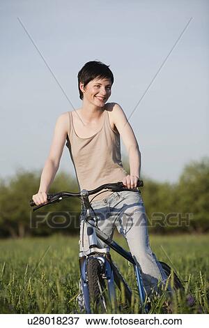 Stock Photo - Russia, Voronezh, woman on bike in field. Fotosearch