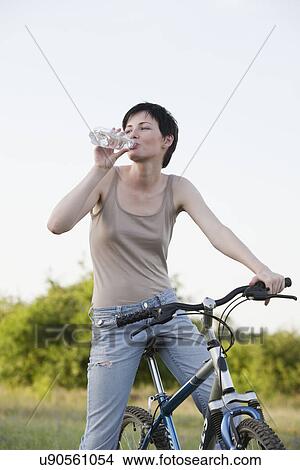 Picture - Russia, Voronezh, woman on bike drinking water. Fotosearch