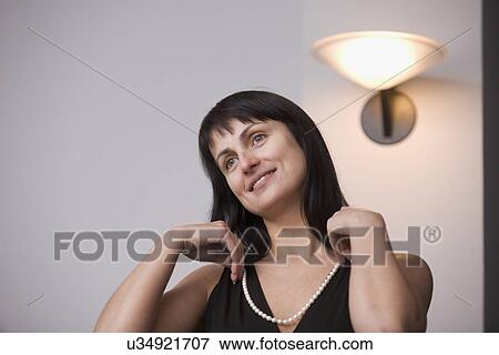 Russia, Voronezh, woman putting on necklace View Large Photo Image Stock Photo - Russia, Voronezh, woman putting on necklace. Fotosearch