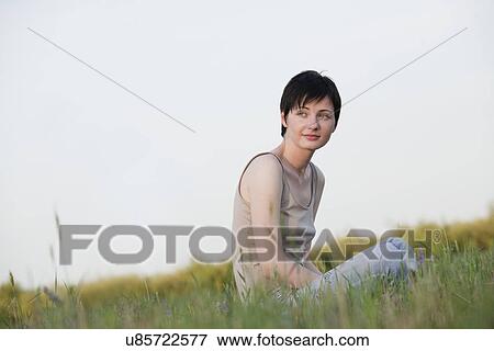 Stock Photo - Russia, Voronezh, woman sitting in meadow. Fotosearch