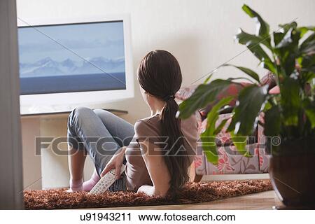 Stock Image - Russia, Voronezh, woman watching TV in room. Fotosearch