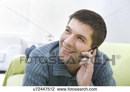 Russia, Voronezh, Young man lying on bed and talking on mobile phone View Large Photo Image Stock Image - Russia, Voronezh, Young man lying on bed and talking on mobile phone. Fotosearch