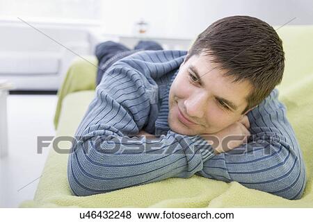 Russia, Voronezh, Young man resting on bed View Large Photo Image Stock Photo - Russia, Voronezh, Young man resting on bed. Fotosearch