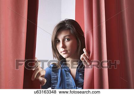 Russia, Voronezh, Young woman peeking through curtain View Large Photo Image Stock Photo - Russia, Voronezh, Young woman peeking through curtain. Fotosearch